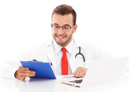 A picture of a happy doctor with laptop and documents sitting in the officeの写真素材
