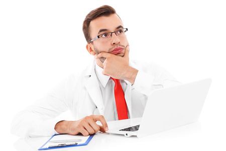 A picture of an unhappy doctor with laptop and documents sitting in the officeの写真素材