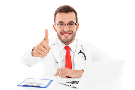 A picture of a happy doctor with laptop and documents sitting in the officeの写真素材
