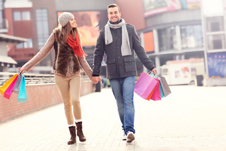 A picture of cheerful young people walking with shopping bags in the cityの写真素材
