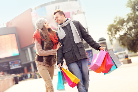 A picture of cheerful young people walking with shopping bags in the cityの写真素材