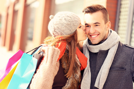 A picture of a beautiful woman kissing a man while shoppingの写真素材