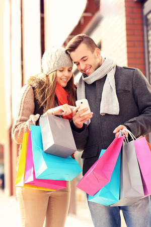 A picture of a couple shopping with smartphone in the cityの写真素材