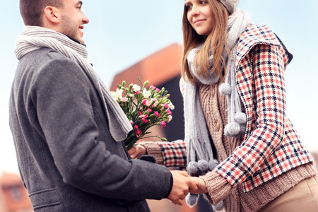 A picture of a romantic couple with flowers meeting in the cityの写真素材