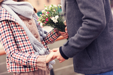 A midsection of a couple holding hands and flowersの写真素材