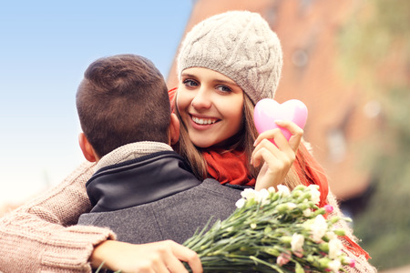 A picture of a happy woman with Valentines gift and flowers hugging her manの写真素材