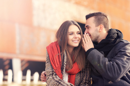 a picture of a young couple whispering on an autumn dayの写真素材