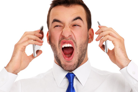 A picture of a furious businessman talking on two phones at the same time over white backgroundの写真素材