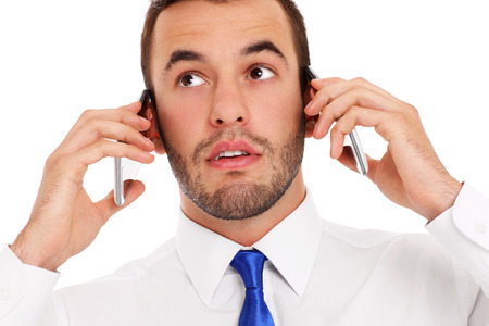 A picture of a furious businessman talking on two phones at the same time over white backgroundの写真素材
