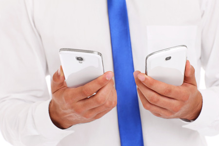A midsection of a businessman with two smarphonesの写真素材