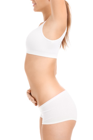 A midsection of a fit woman stretching over white backgroundの写真素材
