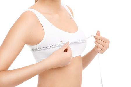 A picture of a fit woman with tape measure checking her bust over white backgroundの写真素材