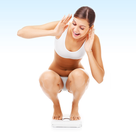 A picture of a shocked woman on a bathroom scales over bluish backgroundの写真素材