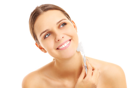 A picture of a pretty woman with a face brush over white backgroundの写真素材