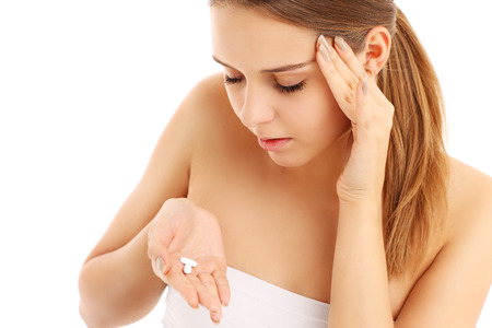 A picture of a woman with headache holding pain killers over white backgroundの写真素材