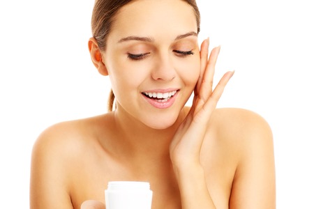 A picture of a pretty woman applying cream on face over white backgroundの写真素材