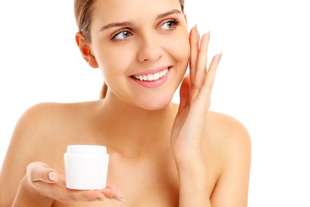 A picture of a pretty woman applying cream on face over white backgroundの写真素材