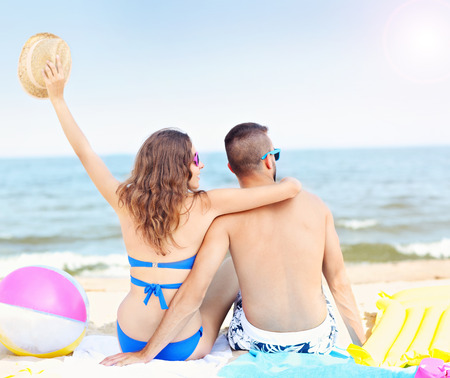 A picture of a young couple sitting on the beach on a sunny dayの写真素材