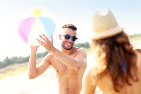 A picture of a young couple playing with a ball at the beachの写真素材