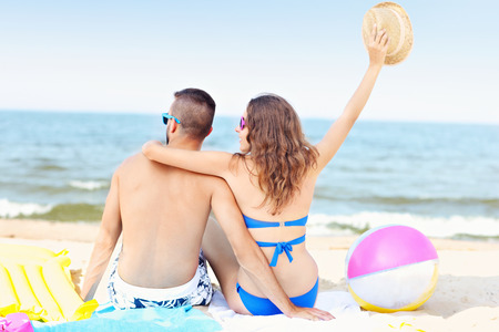 A picture of a young couple sitting on the beach on a sunny dayの写真素材