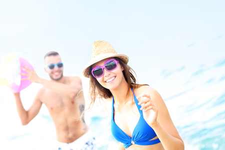 A picture of a young couple playing with a ball at the beachの写真素材