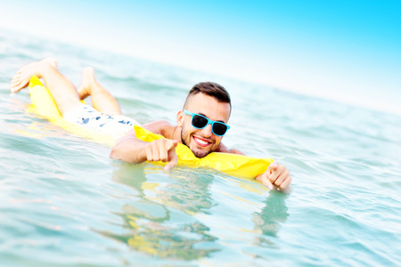 A picture of a young man swimming on a matress in the Baltic Seaの写真素材