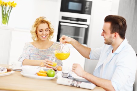 A picture of a young couple eating breakfast in the kitchenの写真素材