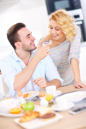 A picture of a young couple eating breakfast in the kitchenの写真素材