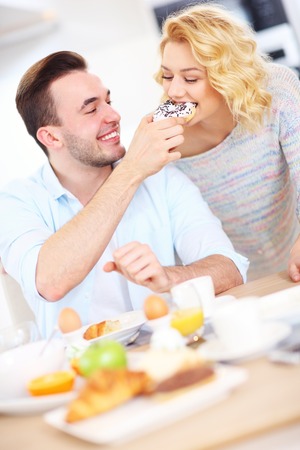 A picture of a young couple eating breakfast in the kitchenの写真素材