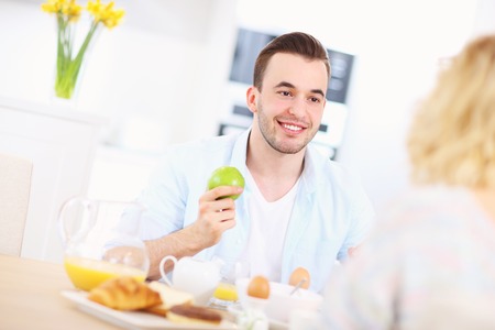 A picture of a young couple eating breakfast in the kitchenの写真素材