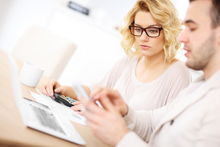 A picture of a worried couple with documents at homeの写真素材