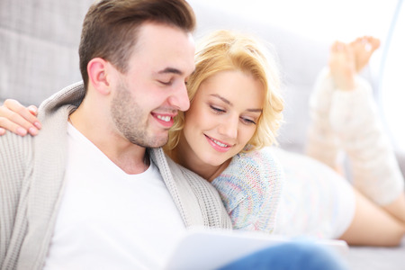 A picture of a romantic couple with laptop in living roomの写真素材