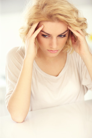 A picture of a young depressed woman with headache at homeの写真素材