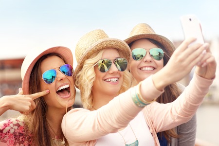 A picture of three friends taking selfie in the cityの写真素材