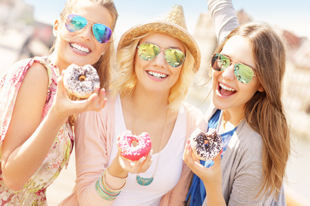 Group of friends eating donuts in the cityの写真素材