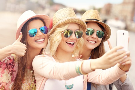A picture of three friends taking selfie in the cityの写真素材
