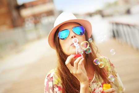 A picture of a happy woman blowing soap bubbles in the city