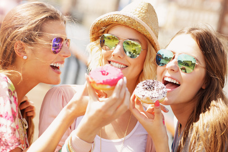 Group of friends eating donuts in the cityの写真素材