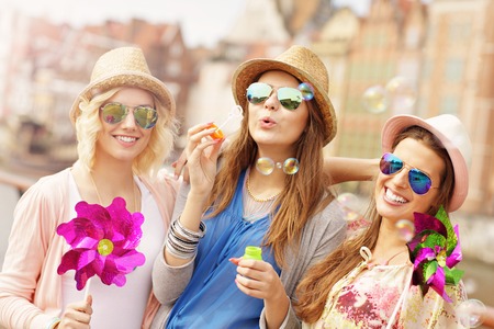 a picture of group of friends blowing soap bubbles in the cityの写真素材