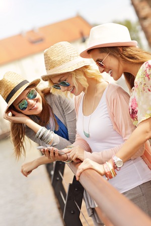 A picture of three friends using smartphone in the cityの写真素材