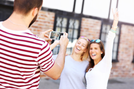 A picture of a group of happy friends taking pictures in the cityの写真素材