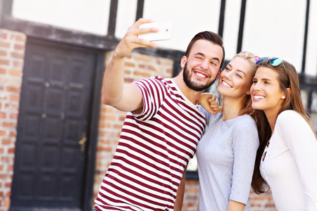 A picture of a group of happy friends taking selfie in the cityの写真素材