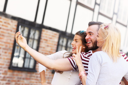 A picture of a group of happy friends taking selfie in the cityの写真素材