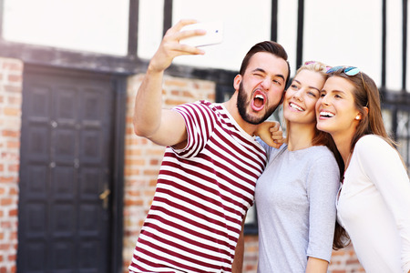A picture of a group of happy friends taking selfie in the cityの写真素材