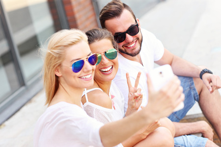 A picture of a group of friends taking selfie in the cityの写真素材