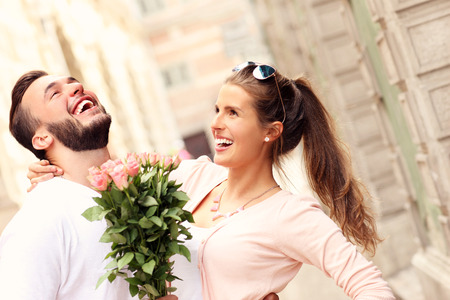 A picture of a young romantic couple with flowers in the cityの写真素材
