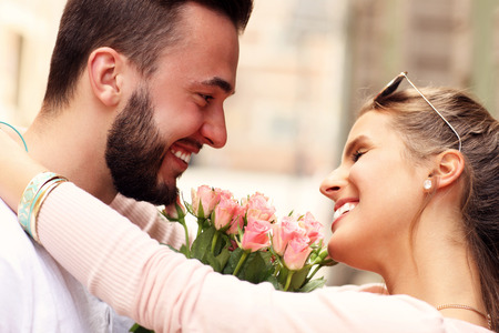 A picture of a young romantic couple with flowers in the cityの写真素材