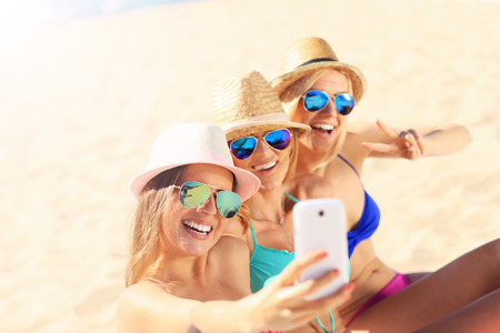 A picture of a group of friends taking selfie on the beachの写真素材