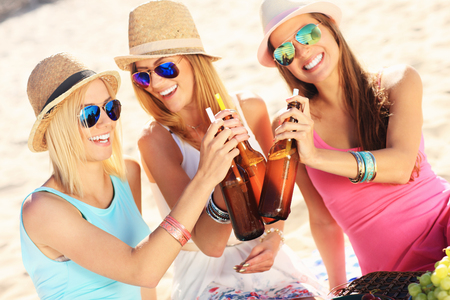 A picture of a group of friends drinking beer on the beachの写真素材