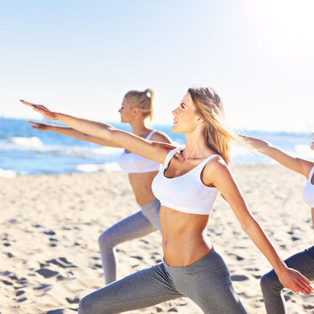 A picture of a group of women practising yoga on the beachの写真素材